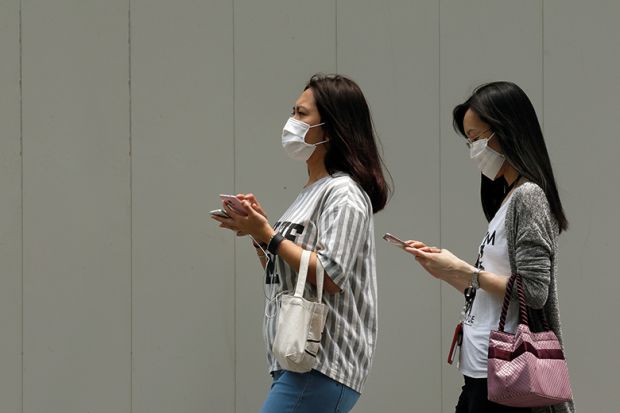 people wearing face masks and using mobile phones in Singapore