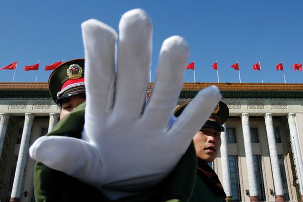 A Chinese paramilitary policeman gestures towards a photographer to stop taking pictures while standing guard at the Great Hall of the People, Beijing