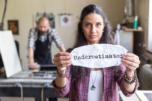 Young female lithography worker holding a sign "underestimated"