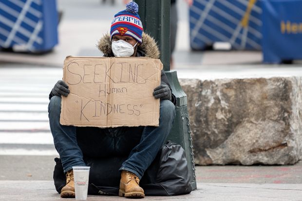 A homeless person wearing gloves and a protective mask sits with a sign that reads, "Seeking Human Kindness" amid the coronavirus pandemic on April 19, 2020 in New York City, United States. 
