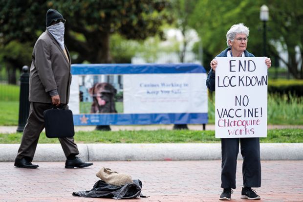 A lone protester holds a sign calling for an end to the lockdown and claiming chloroquine works as she stands in front of the White House in Washington on Saturday, April 25, 2020.