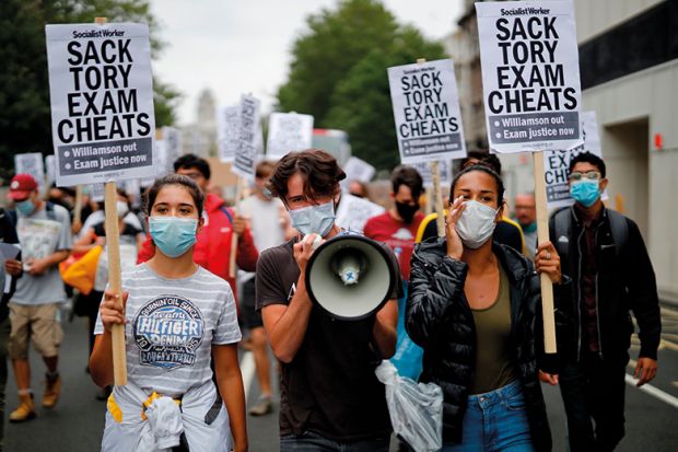 Students hold a placards as they march in central London on August 14, 2020 to protest against the downgrading of A-level results