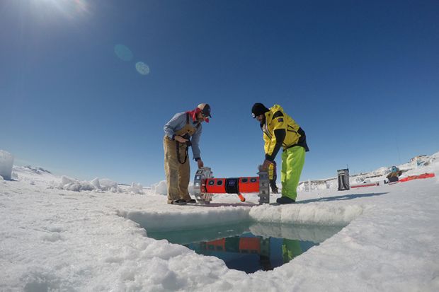 Kevin Hand and Dan Berisford prepare to deploy their under-ice roving robot (BRUIE) through a hole in the sea ice in Antarctica