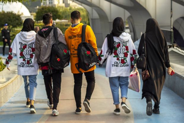 The youth in Tehran stroll through the city. A cheerful group of Iranian young people. Back view.