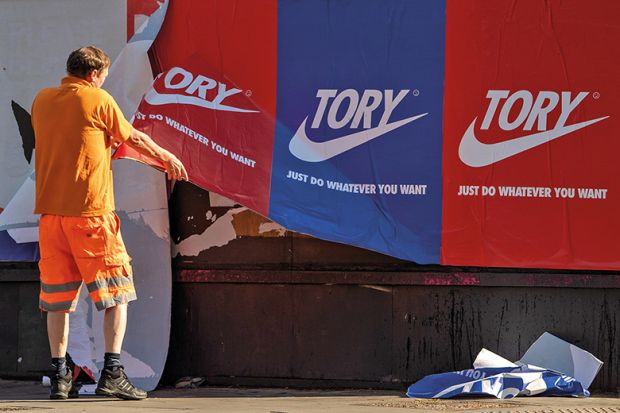 A maintenance worker removes posters depicting the Nike logo and reading ‘Tory just do whatever you want’ from a wall in Shoreditch, East London, on May 30, 2020, England.
