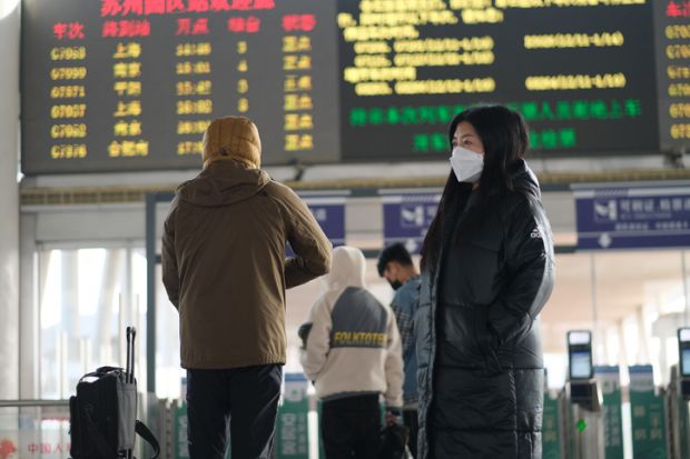 A traveller in a face mask at a railway station in Suzhou, China, illustrating the downturn in Chinese international students post-Covid