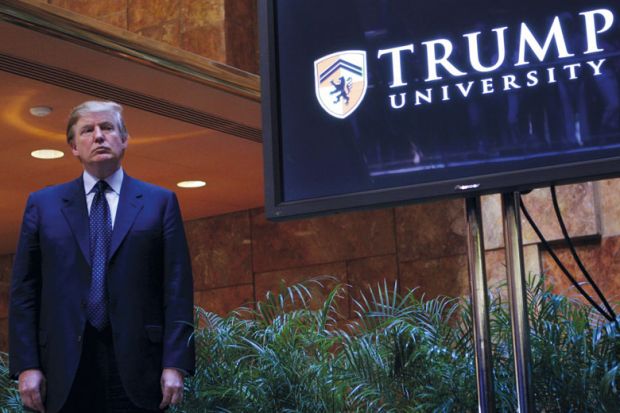 Donald Trump standing by a Trump University sign in New York City to illustrate Trump’s American Academy: pure politics, or valid idea?