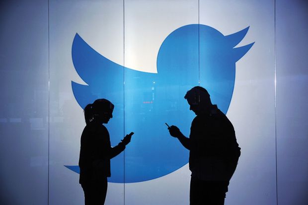 Two people silhouetted against Twitter logo
