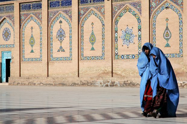 Two women walk in front of the Great Mosque of Herat in Herat, Afghanistan