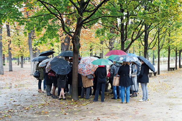 Group of people sheltering under umbrellas