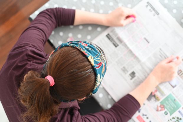 Unemployed woman searching for job in local newspaper