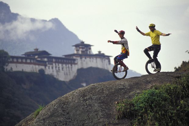 Two unicyclists on a hill