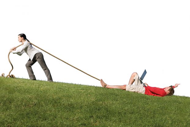 A woman drags a man uphill on grass using a rope