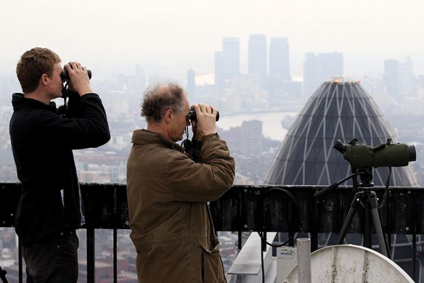 Birdwatchers use binoculars to observe birds from the top of Tower 42, London, illustrating UK institutions seeking to hire EU professors and postdocs