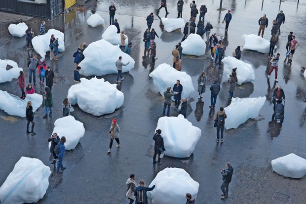 Visitors interact with blocks of melting ice from an exhibit outside Tate Modern in central London to illustrate A measure of reality