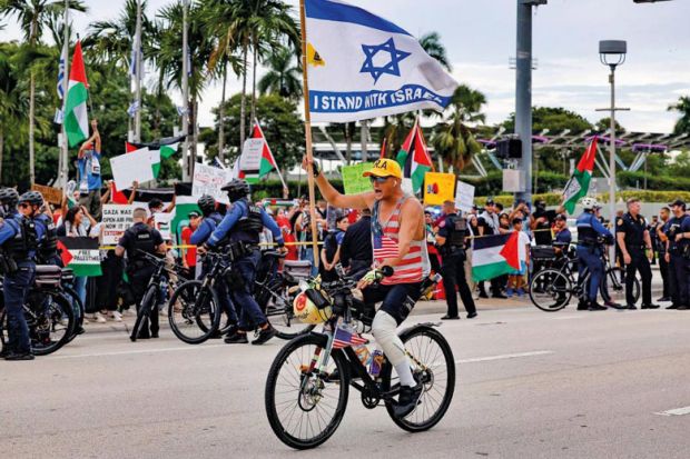A pro-Israel protestor rides his bike along Biscayne Blvd to illustrate US campuses confront extent of donor influence after Israel rows