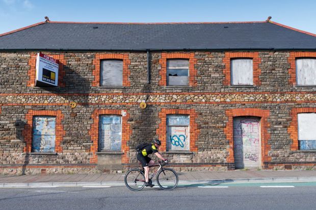 A cyclist rides past a boarded up retail unit to illustrate UK’s university investment zones echo US, but leave questions