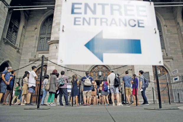 Tourists wait in line outside the Notre-Dame Basilica in Montreal, Quebec, Canada to illustrate Universities blindsided as Quebec set to double non-