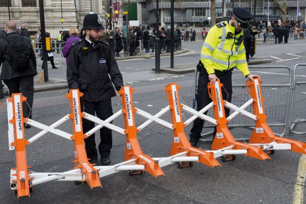 Met police officers drag barriers  into place to illustrate opposition in Whitehall to Home Office plan for graduate visa limits