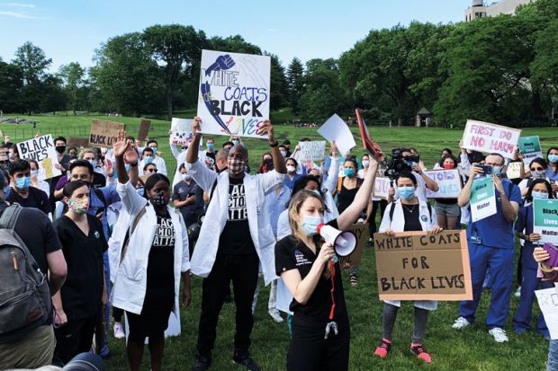 Medical workers in face masks hold signs reading White Coats for Black Lives as a metaphor for US medical schools found to be falling short on equity promises