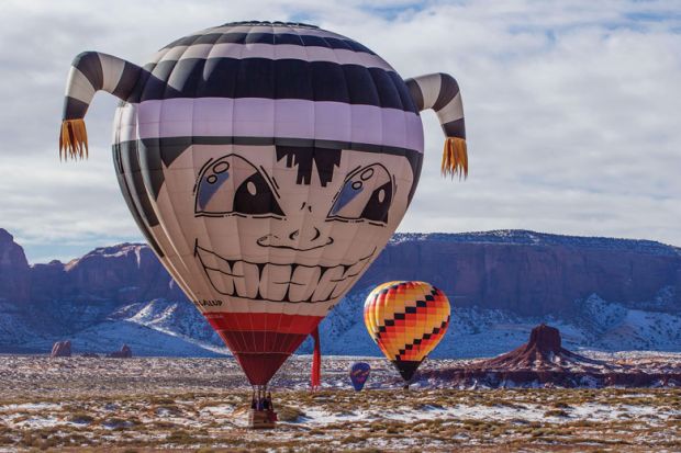 Hot air balloon flying low in Monument Valley Navajo Tribal Park in Arizonal as a metaphor for up, up and away