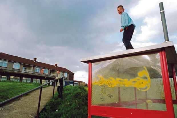 Boys playing on bus shelter on run down council estate; Bradford UK to illustrate social mobility