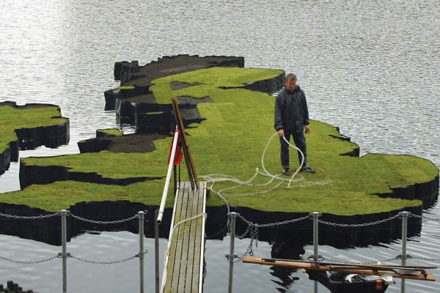 A man waters an island which has been designed in the shape of the United Kingdom to illustrate Indian Institutes of Technology set to open UK branches