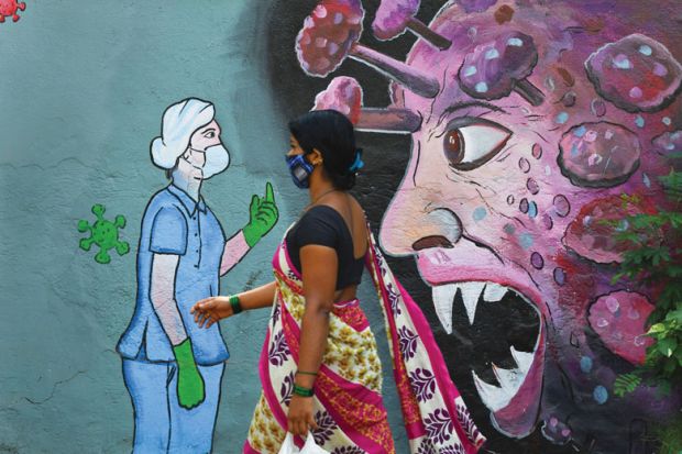 A pedestrian walks past a wall mural depicting a frontline medical staff stopping the Covid-19 as a metaphor for Research on viruses is  essential but can never be risk- free