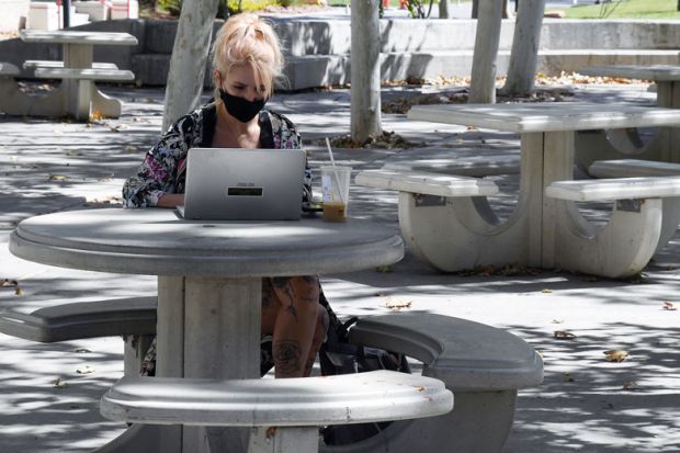 Student works on a laptop in a courtyard on campus to illustrate US students make gains in lawsuits over online teaching