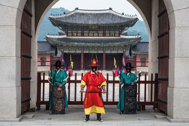 Guards of Gyeongbokgung Palace wearing face masks with traditional pattern stand at the gate of the palace to illustrate Welcome foreigners to avoid demographic cliff edge, Korea told