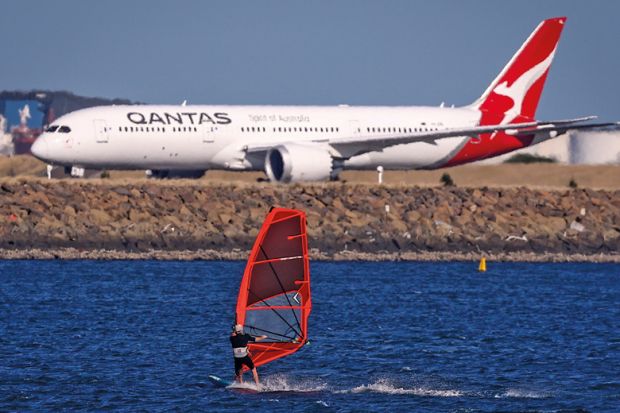 A sail boarder rides in front of a Qantas Airways plane to illustrate New Colombo Plan changes will reverse equity gains