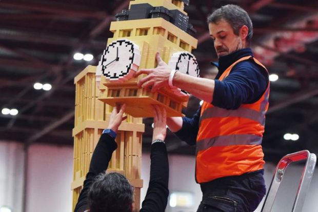 An exhibitor puts the finishing touches to a model of the Houses of Parliament's Elizabeth Tower (Big Ben) made from Lego to illustrate Embedded inside parliament, influence of academics grows