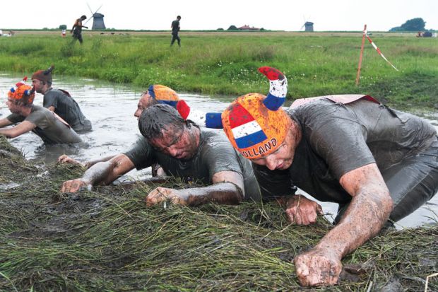 Participants of the traditional mud marathon in Schermerhornon pulling themselves up as a metaphor for recognising “team spirit”