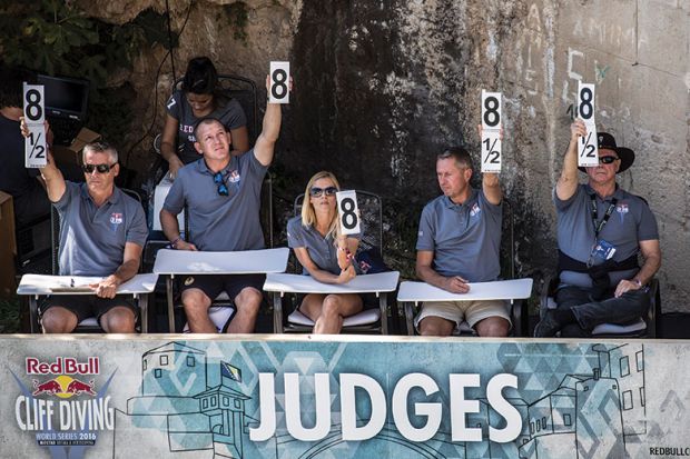 Row of judges hold up cards with numbers for a cliff diving competition as a metaphor for titles at stake in Australian audit