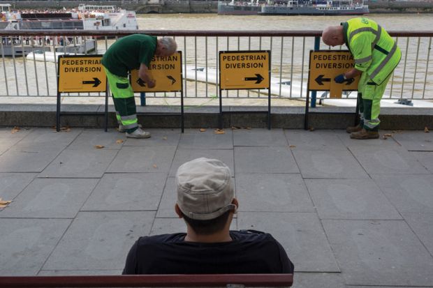 Workmen adjusting diversion arrows signs to illustrate ‘Mixed messages’ on face coverings on campus ‘harms compliance’