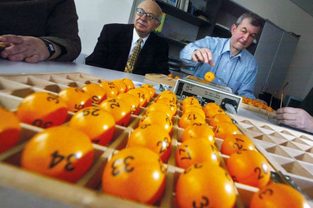 An official prepares lottery balls to illustrate British Academy trials awarding research grants by lottery