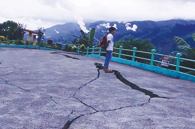 Person stands next to cracks in the ground at a park in Leyte province, central Philippines as a metaphor for the pan-regional university risks being split by the same tensions