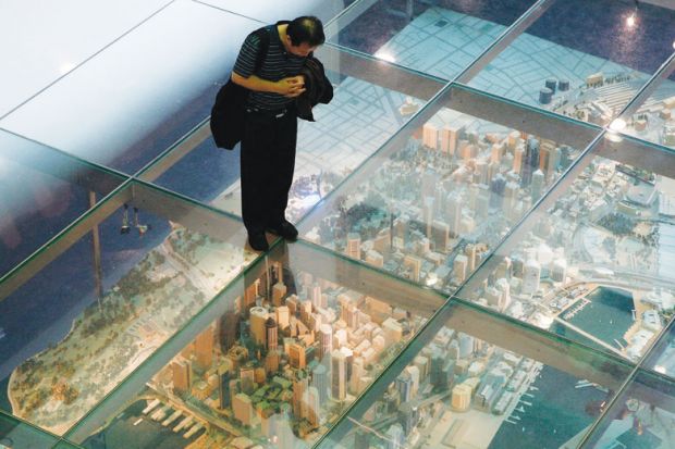 Person looks at a model of Sydney's central business district in central Sydney under a glass floor as a metaphor for China moves to halt universities’ eastern branch campus rush