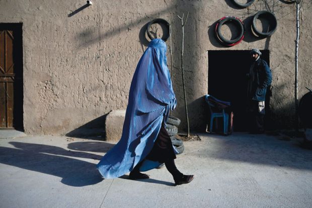 A woman wearing a burqa walks along a road at the Khwaja Koza Gar area in Herat to illustrate Segregation and half-empty campuses as Afghan universities reopen