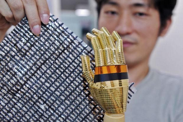 Tokyo University researcher shows a sheet containing carbon nano tubes and a robot hand
