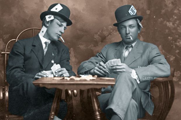 Two young men pretending to play cards. They are smoking and they sit close to a small table. Both men wear hats and have their legs crossed. One man is peeking into the other's card hand. Both guys have aces, kings and other cards visibly hidden in all p