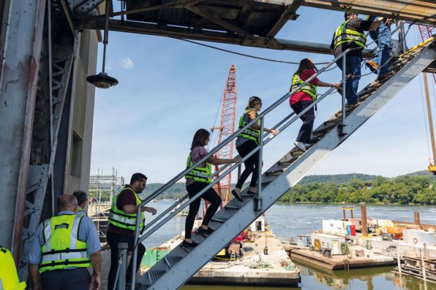 People climb up to the dam during a tour of Montgomery Locks and Dam on the Ohio River in Monaca, Pennsylvania to illustrate National Institutes of Health weighs pay hike for postdocs