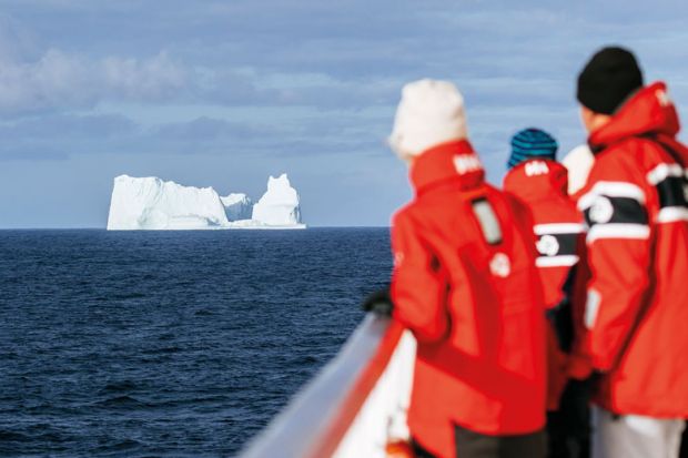 People looking at an iceberg in the distance to illustrate Icebergs, straight ahead