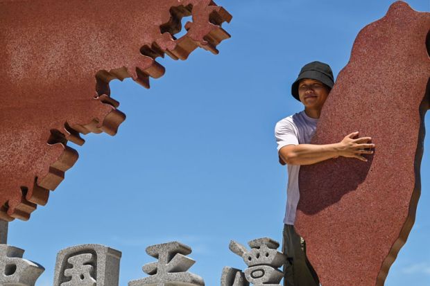 A tourist poses with a monument representing mainland China to illustrate Taiwan-Beijing tensions ‘could rattle international students’