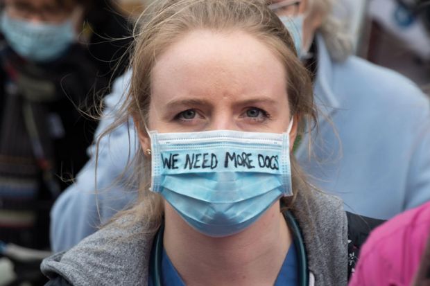 A woman doctor wears a surgical mask with the writing 'We need More Docs' to illustrate More medical students ‘won’t solve doctor shortage alone’
