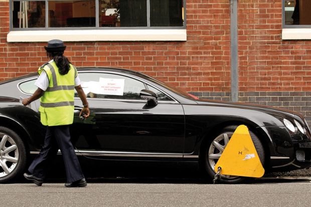 A parking enforcement officer walks past a car with a wheel clamp to illustrate High impact and low quality linked