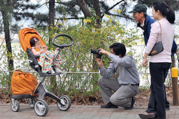 A South Korean man takes a photo of his baby sitting on a pushchair during their family picnic to illustrate Korean excellence plan shortlist drafted
