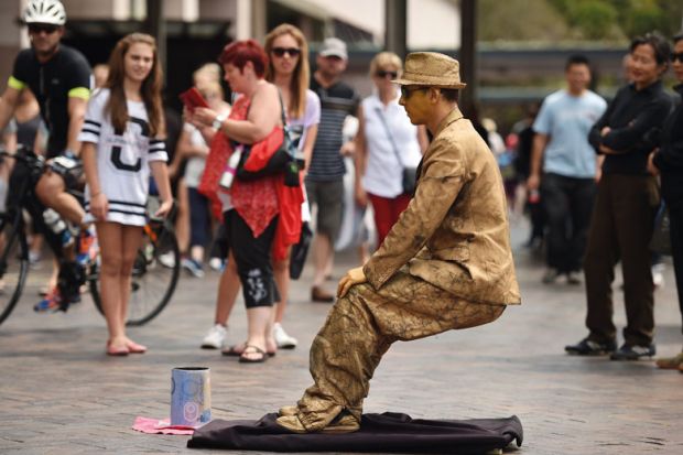 Tourists watch a mime artist perform in Sydney to illustrate Australian vice-chancellors’ pay rises ‘paused’ post-pandemic