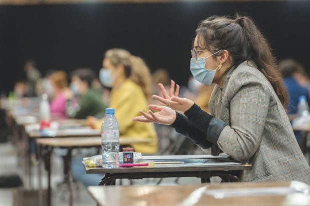 Student wearing mask at the desk in an exam hall as a metaphor for a test of resilience