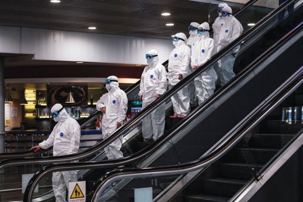 Medical staff wearing protective suits ride down an escalator for Leadership turnover rate could double